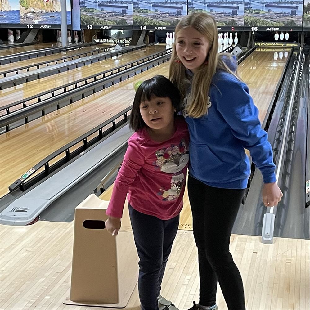  two students with bowling lanes behind them