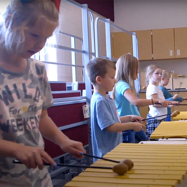  Children playing xylophone in school.