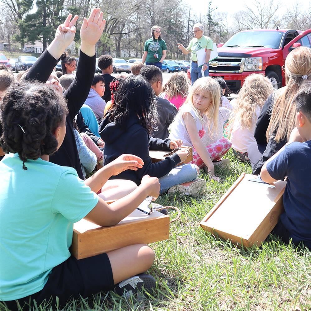  Students listening to a speaker holding new outdoor desks